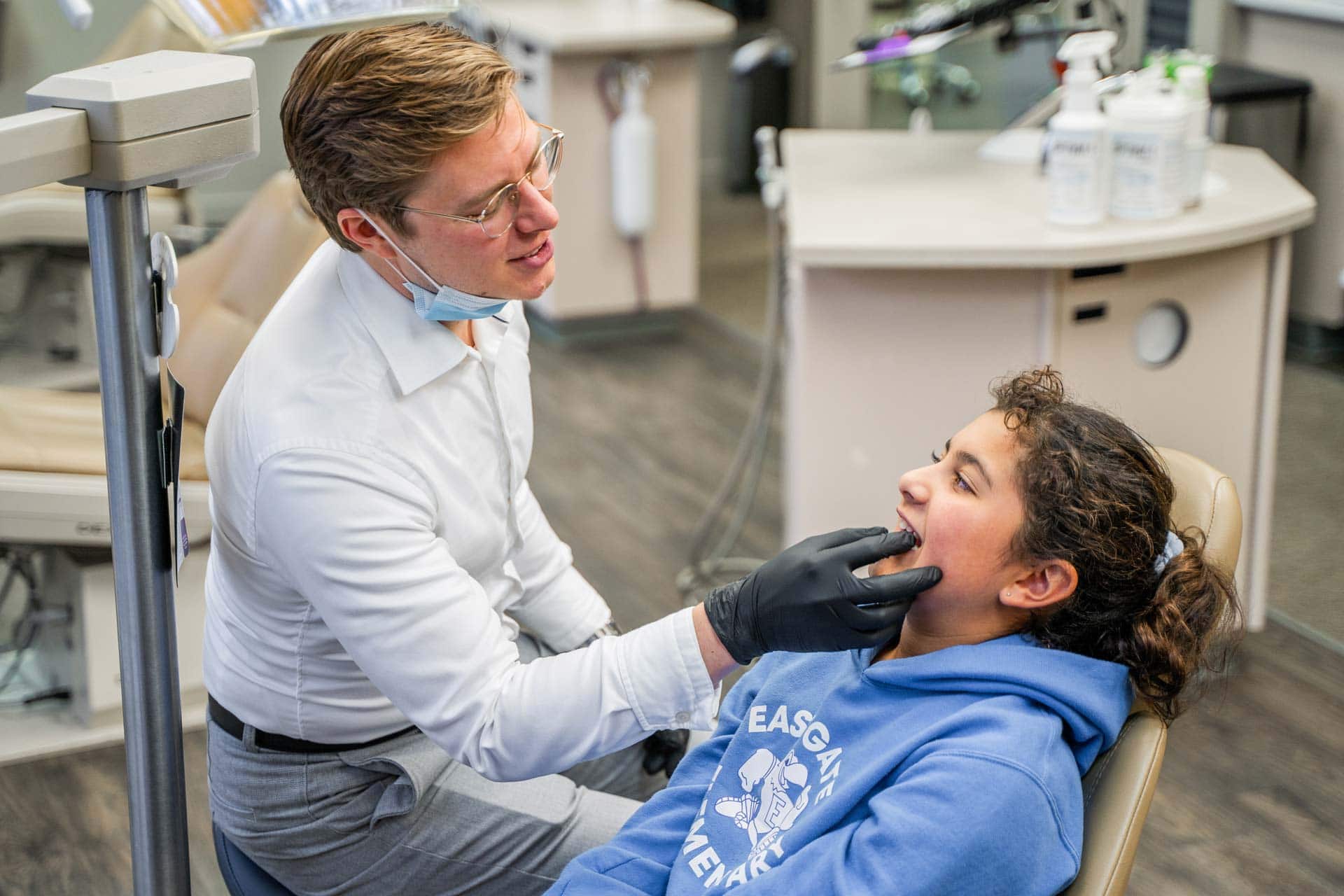 Dr. Adam examines a young girl in a dental office.