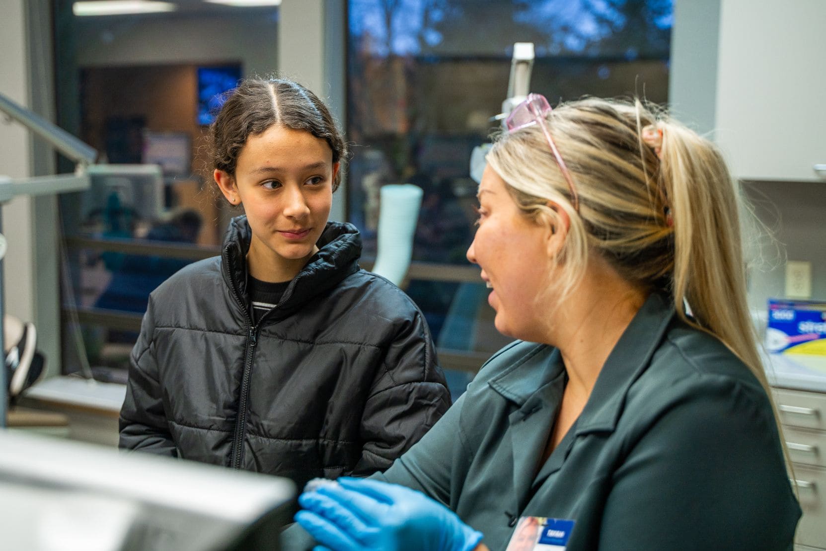 A young girl is talking to a staff member in the office.