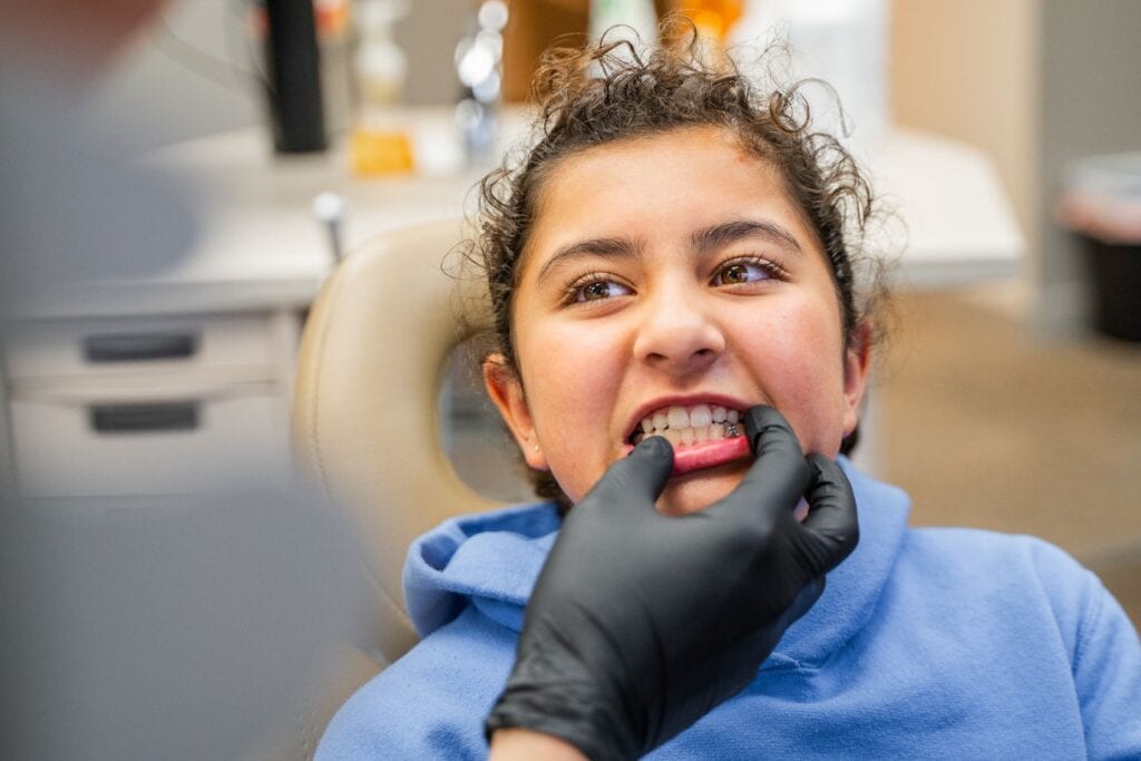 A young girl getting her teeth checked by the doctor.
