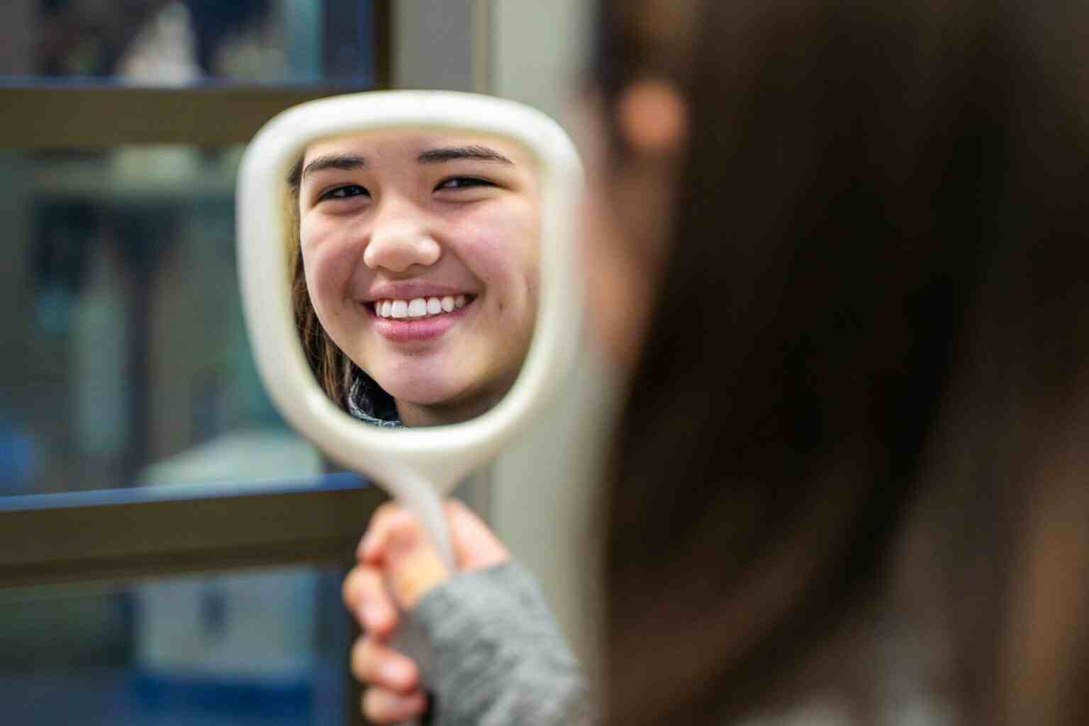 A woman is looking at herself in a mirror.